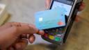 Close-up of human hand holding credit card over contactless credit card reader to pay for shopping