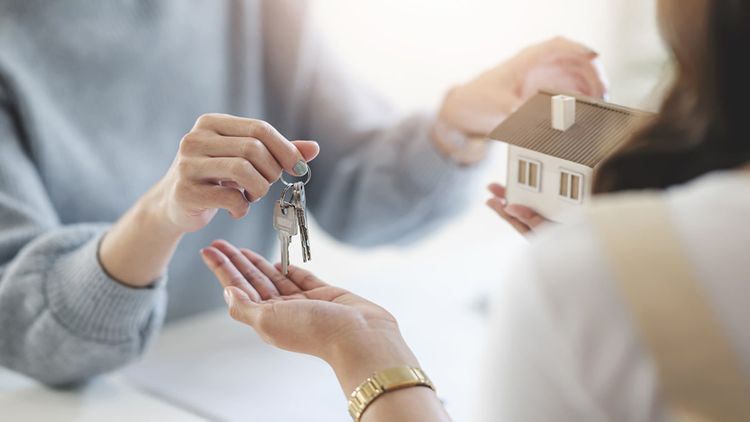 Close up of woman buying home, exchanging keys with real estate agent.