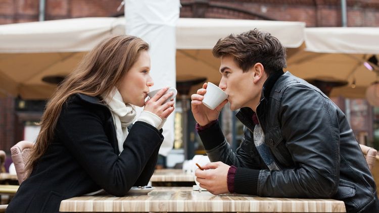Man and woman on a date drinking coffee together outside