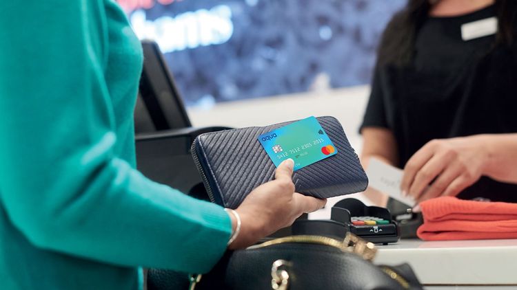 Close-up of adult woman holding purse and credit card while shopping and paying in a retail store.