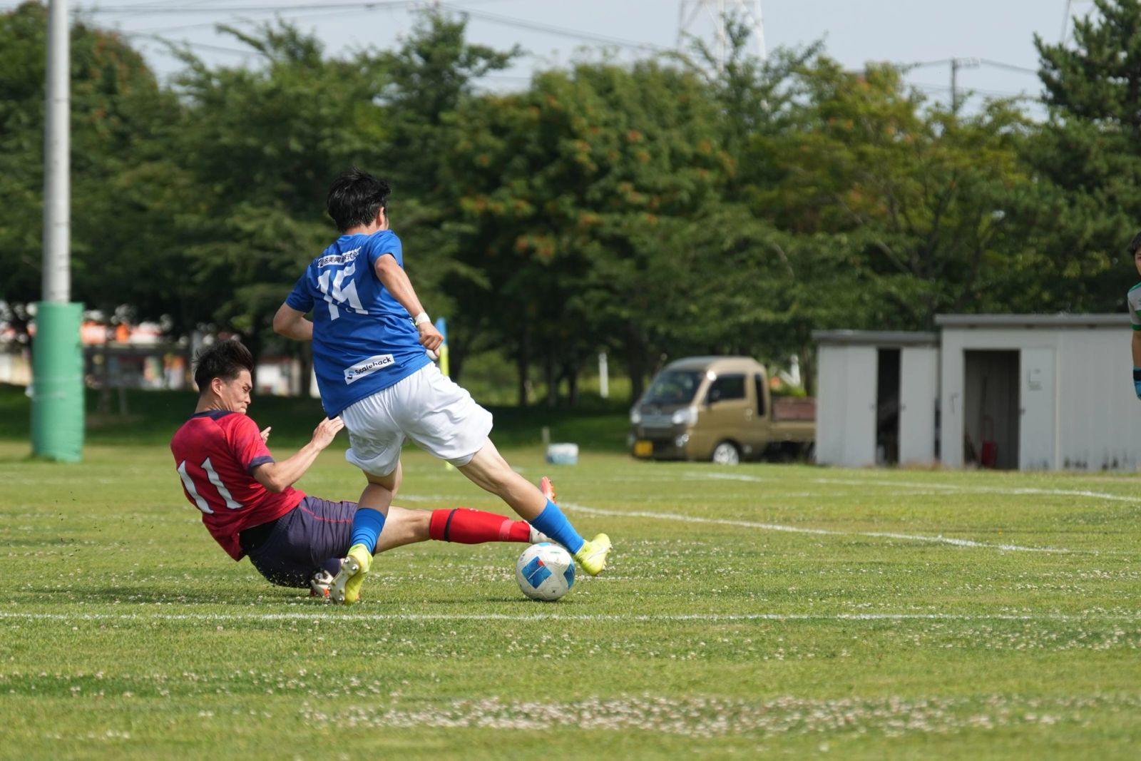 スライディングをかわしてボールを運ぶ選手
