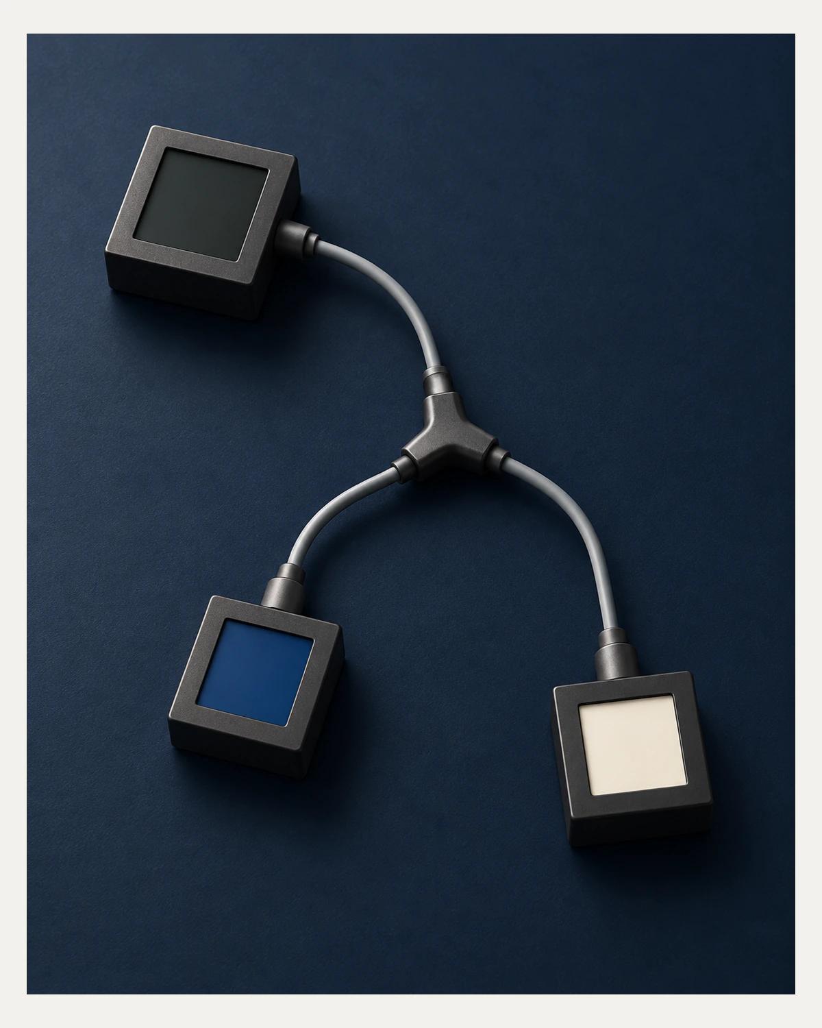 A graphite block connects through grey cables and a Y-junction to two lower blocks with cobalt and ivory insets on a navy surface.