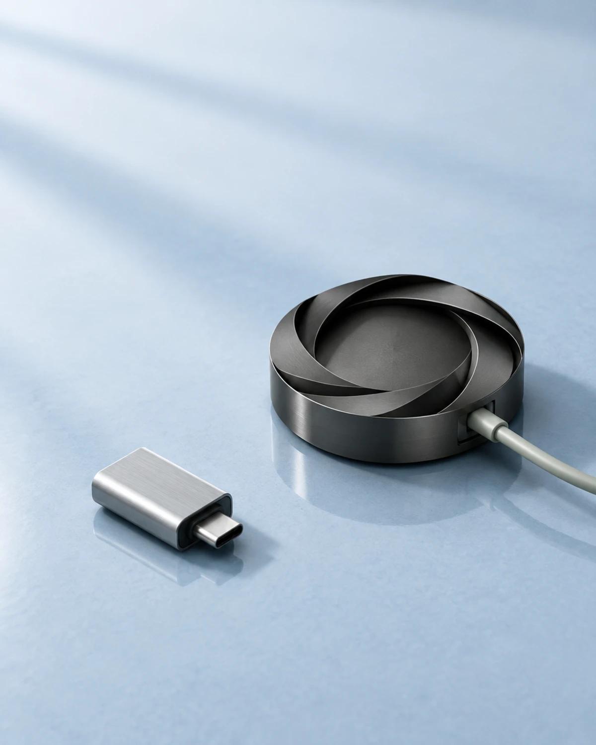 A graphite network junction with one connected cable and a separate portable adapter on a pale surface.