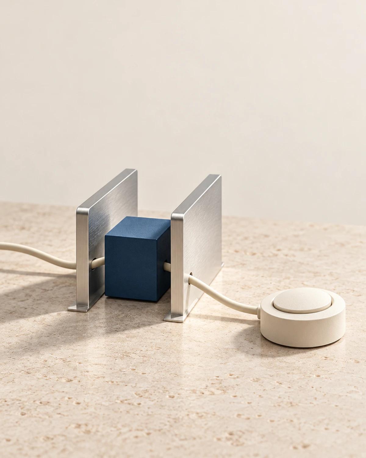 A cobalt block between two aluminium rails connected to a separate ivory switch on pale stone.