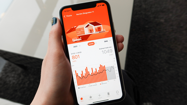En hånd som holder en telefon med Fjordkraft-appen åpen