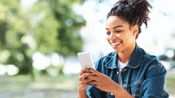 Smilende dama med en mobil i hånden som hun ser på