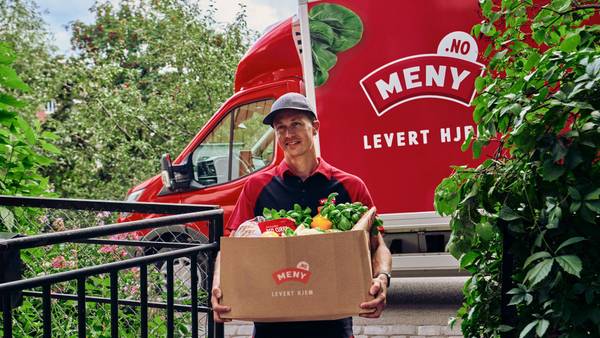 Smilende MENY ansatt leverer varer fra MENY helt hjem til kunde