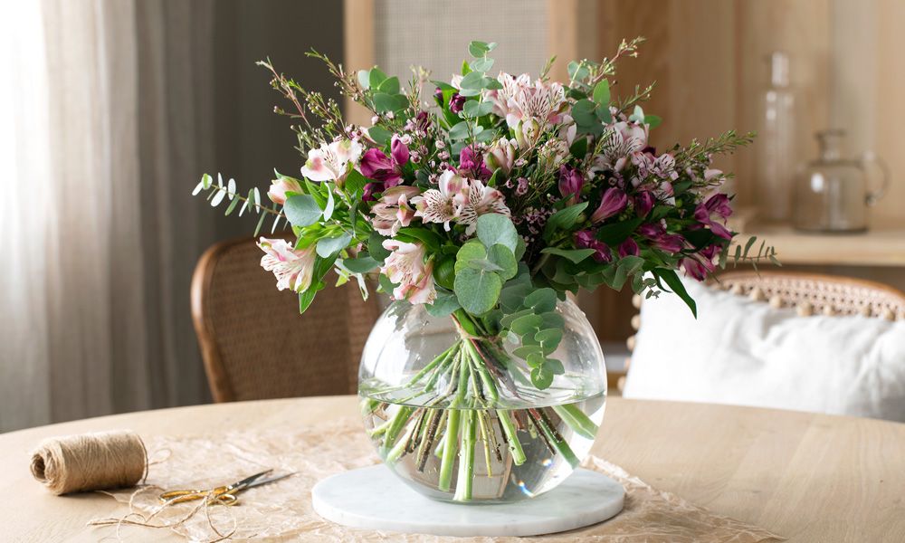 Vakker blomsterbukett fra Mester Grønn i vase plassert på et bord i en stue