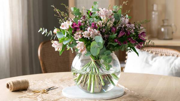 Vakker blomsterbukett fra Mester Grønn i vase plassert på et bord i en stue