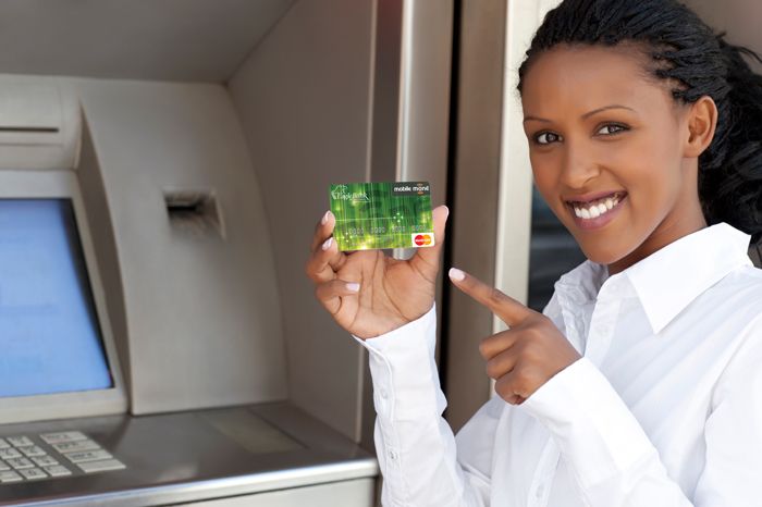 Woman holding a green bank card beside an ATM