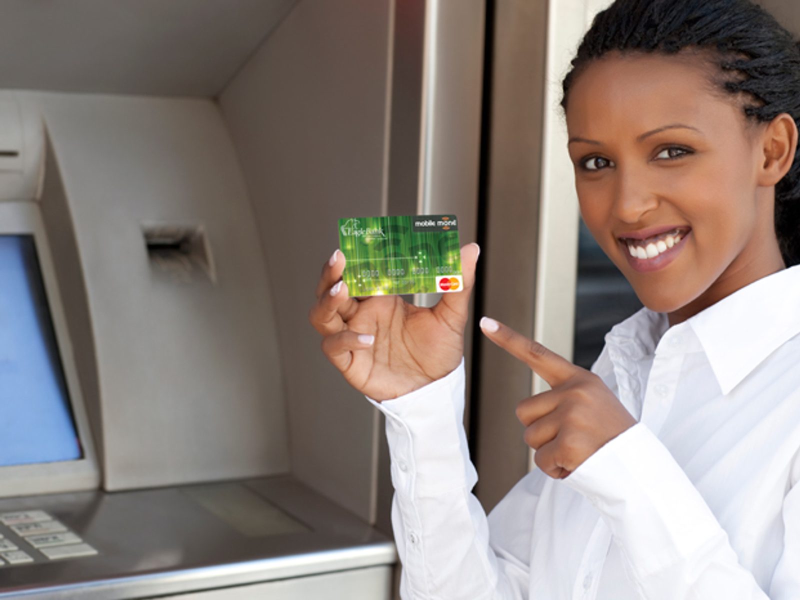 Woman holding a green bank card beside an ATM