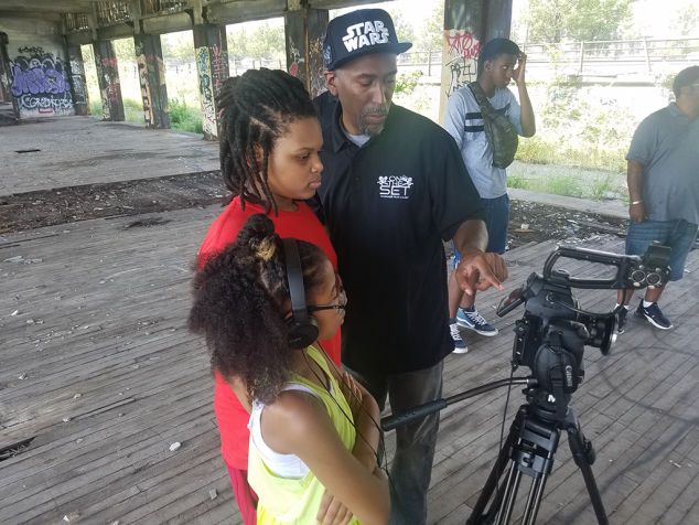Young film participants and an instructor working beside a professional camera