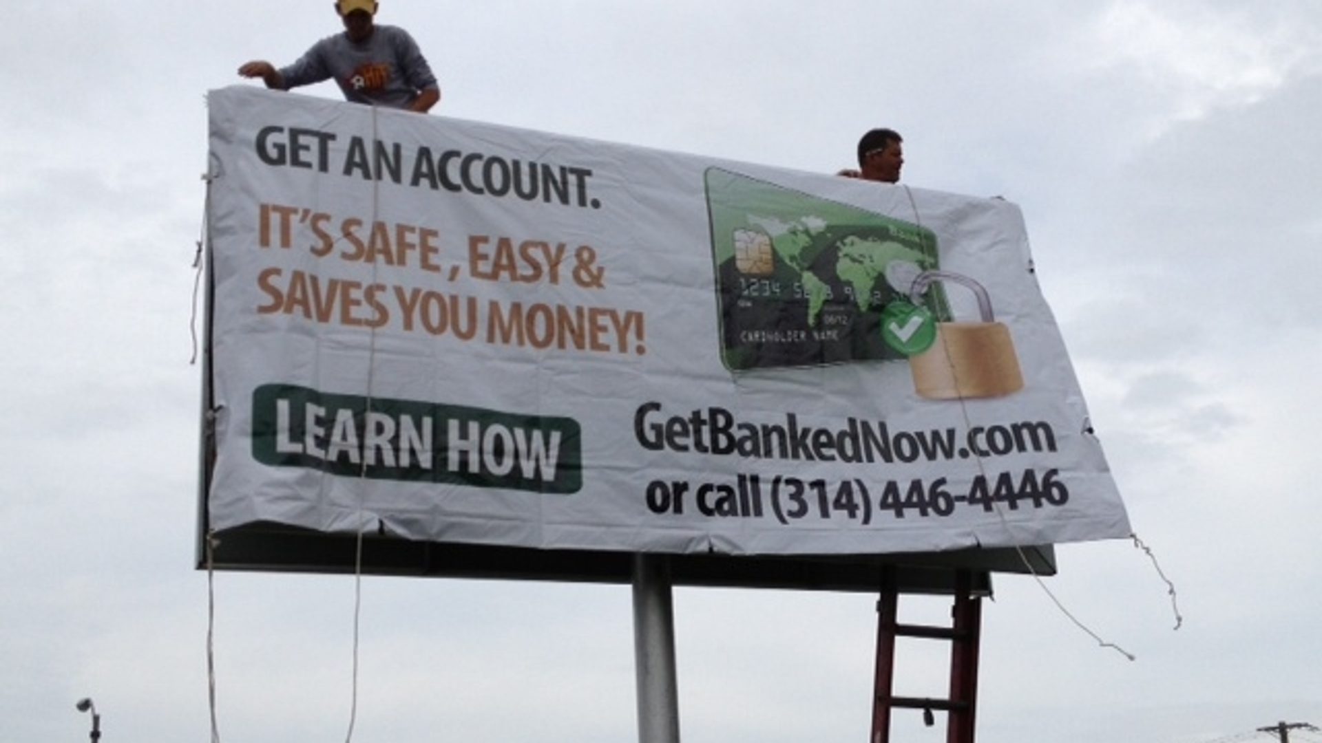 Bank On Save Up billboard being installed above a roadway