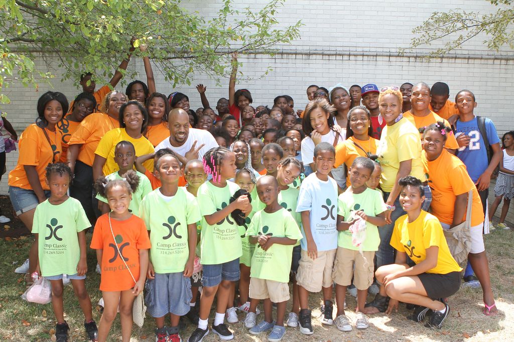 Children and adults posing together outdoors in matching yellow shirts