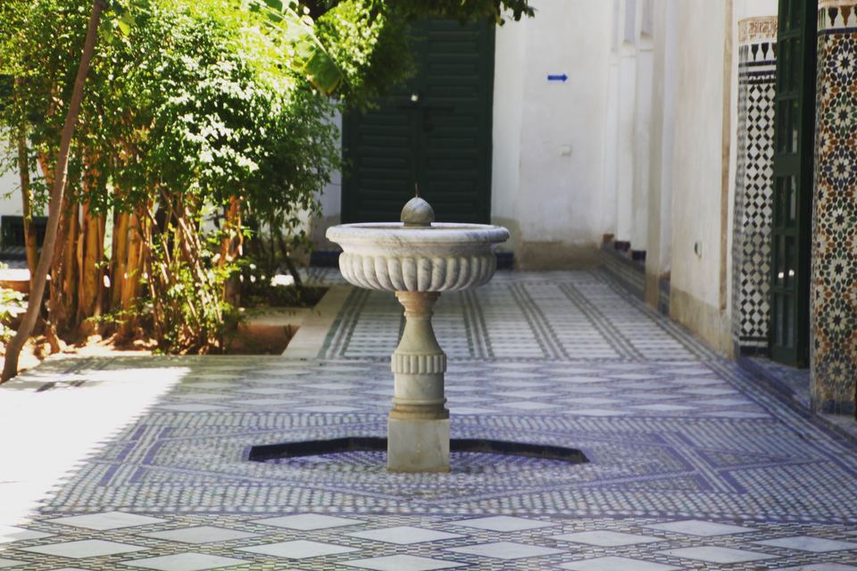 Marble fountain on a zellige-paved path in an inner garden