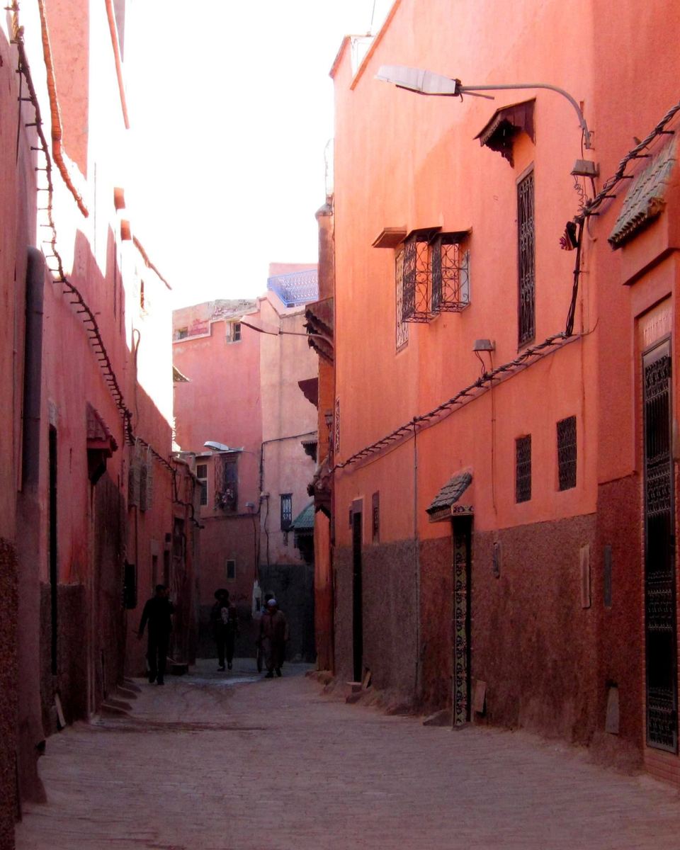 Derb étroit de la médina de Marrakech entre de hauts murs ocre et rouges, lumière rasante