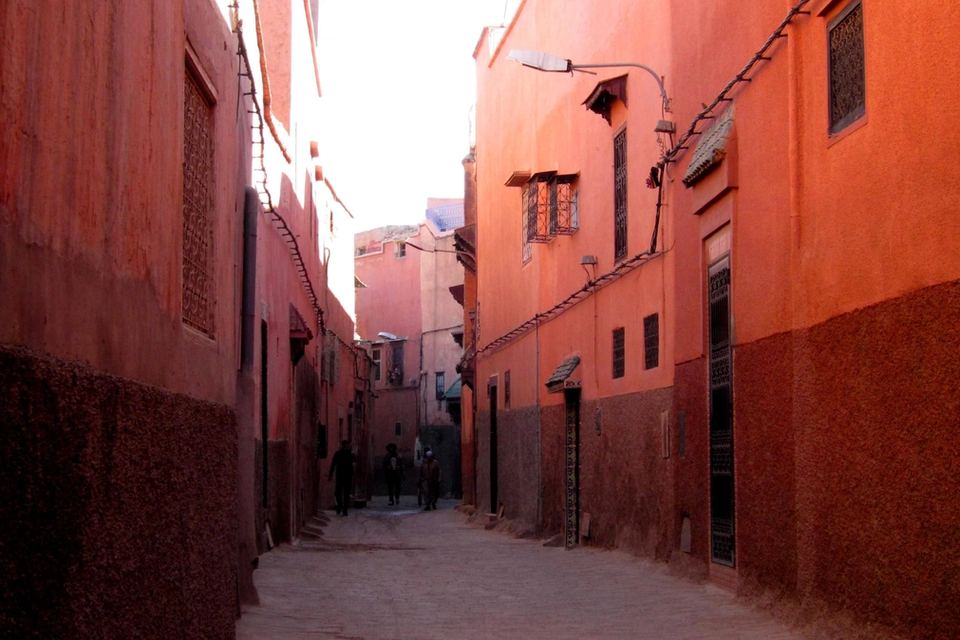 Derb étroit de la médina de Marrakech entre de hauts murs ocre et rouges, lumière rasante