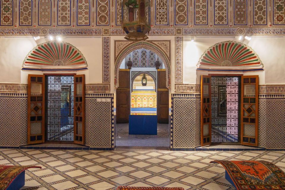 Room with traditional Moroccan decoration: zellige, painted stucco, wooden doors and antique rugs