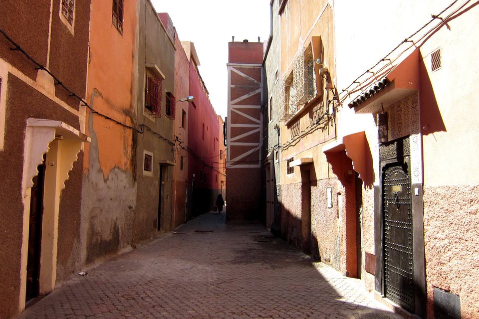 Quiet alley in the Marrakech medina, lined with ochre façades and a carved wooden door