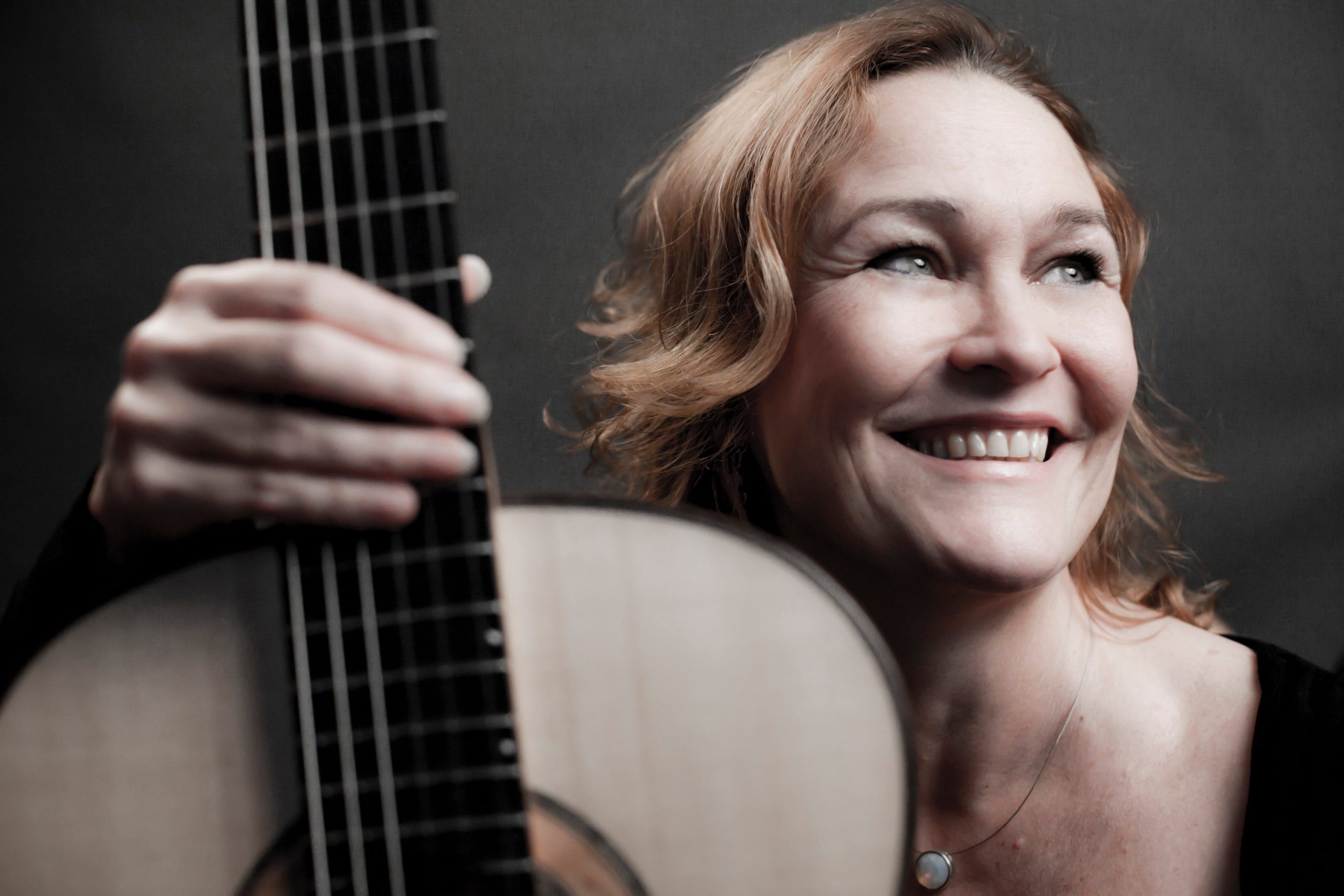 Marion Schaap looking very happy while holding her guitar close to the camera