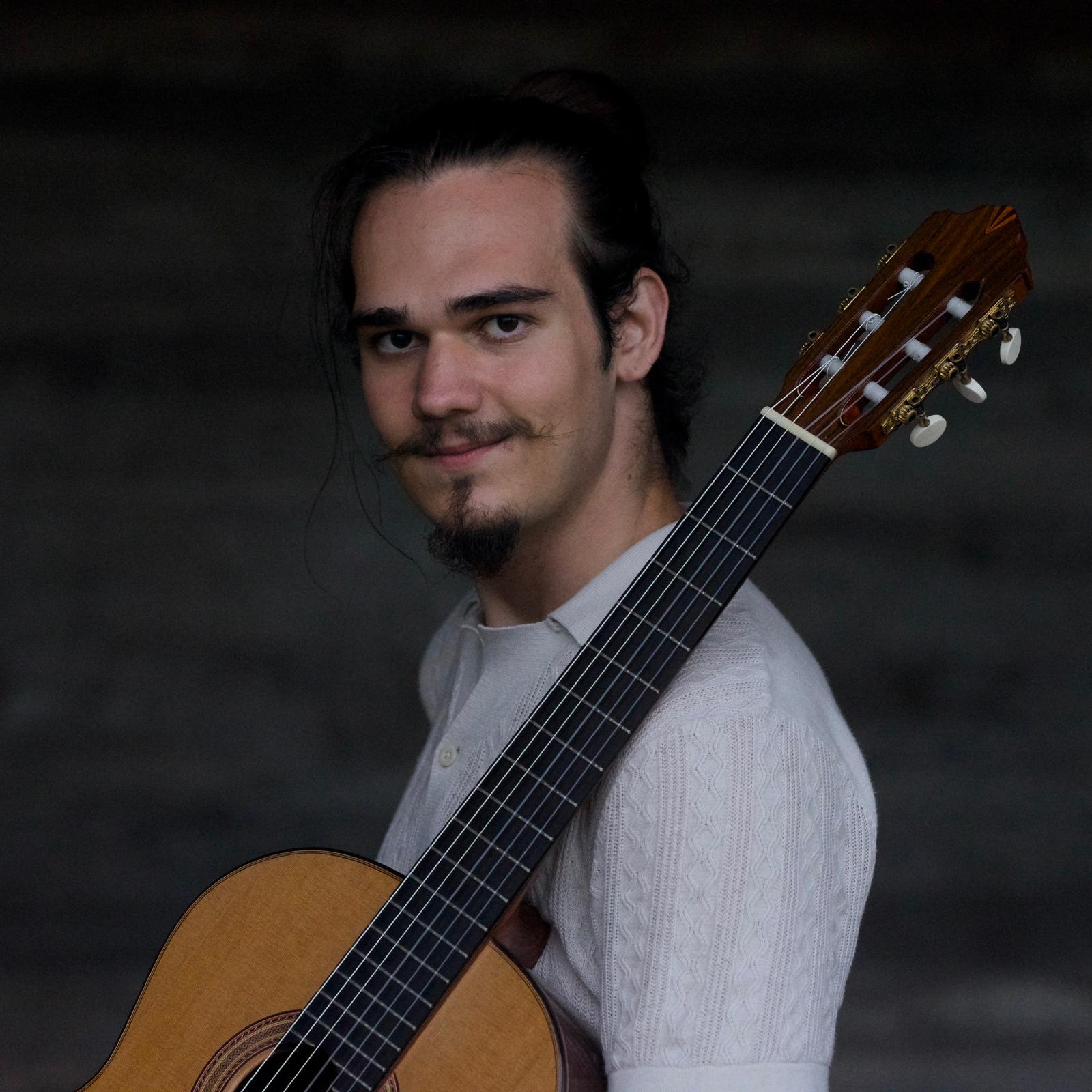 Viktor in front of his guitar with a soft smile.