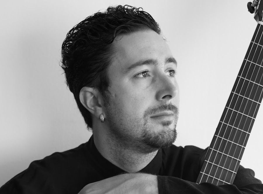 Dani Sehu looking distant while holding a guitar.