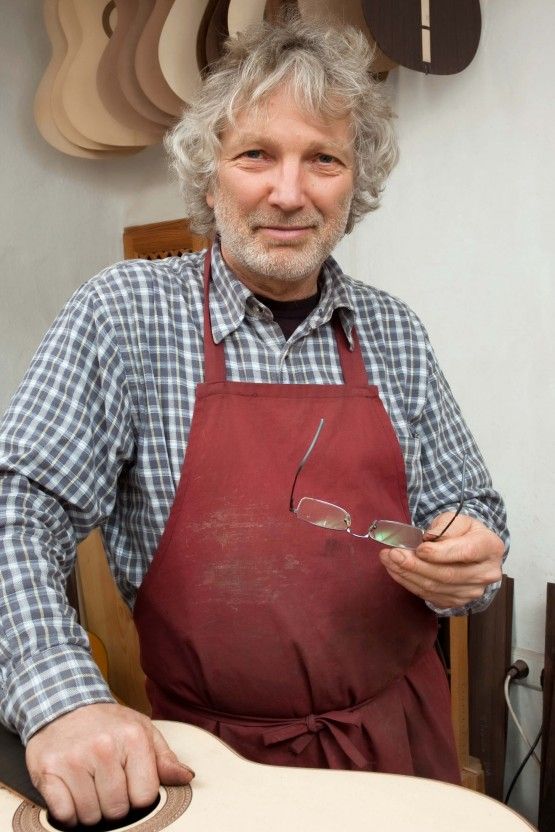 Marvi in his guitar workshop looking at the reader in the middle of building an awesome guitar.