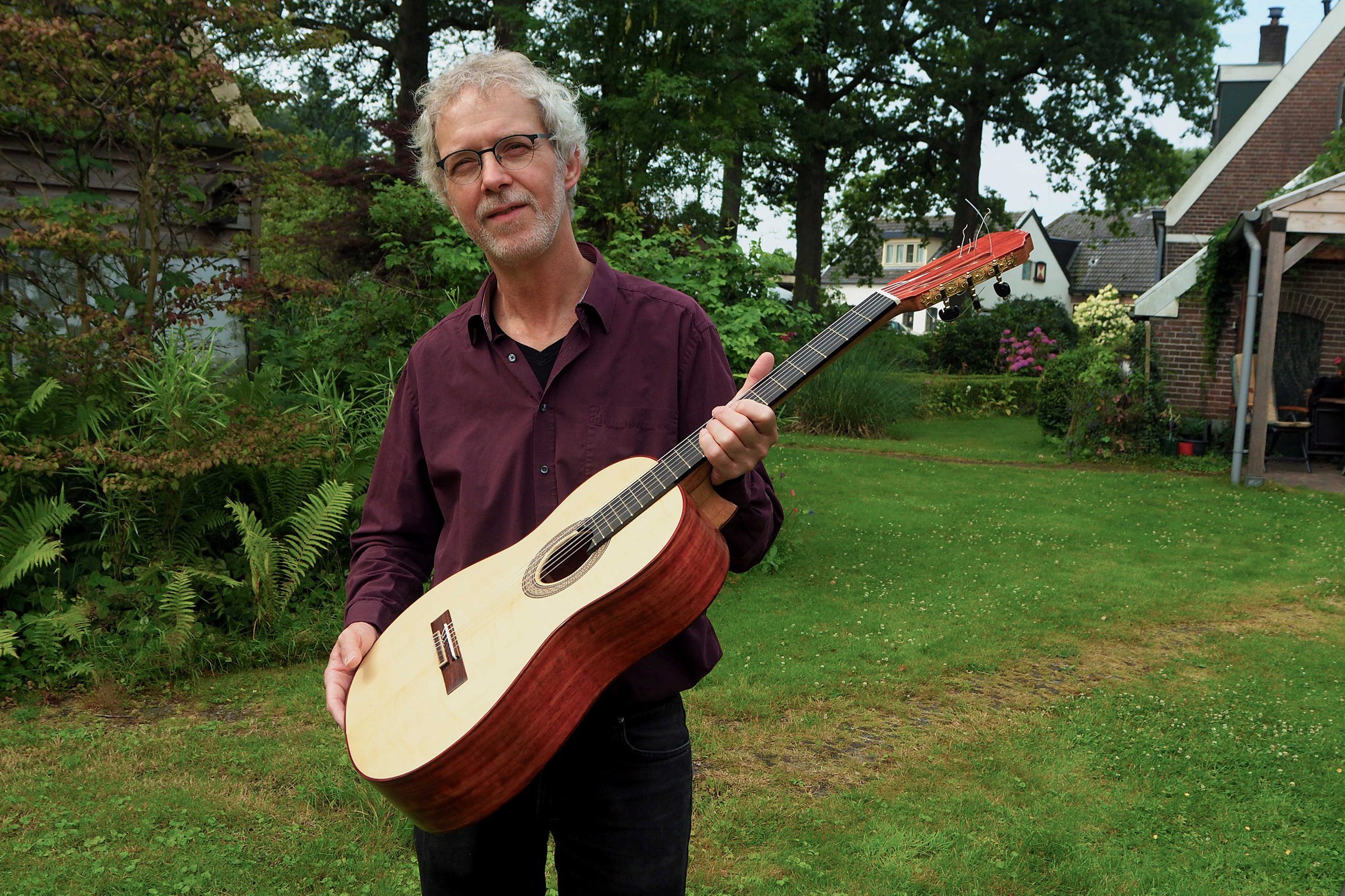 Jan standing outside holding one of his guitars.