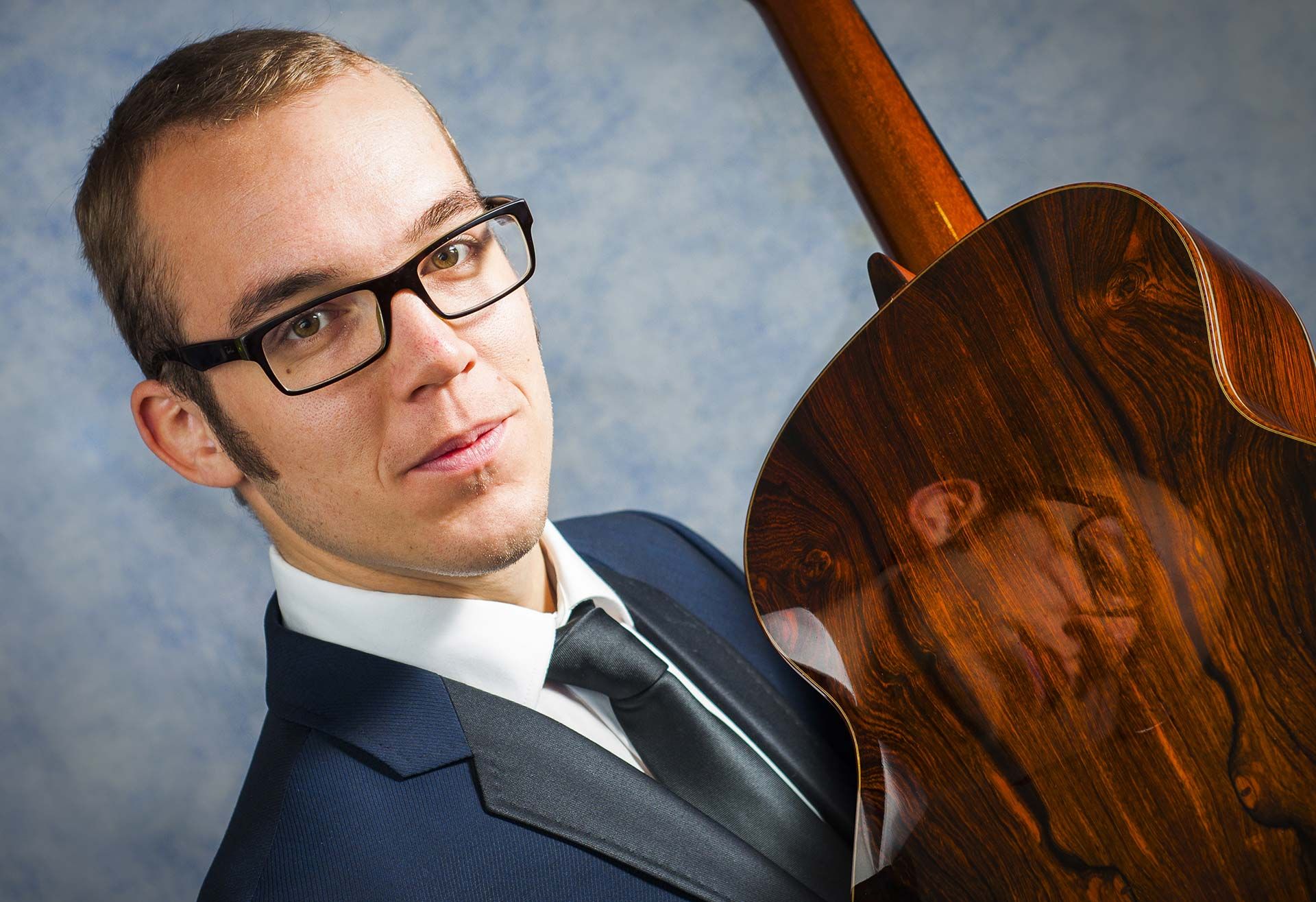 Martin van Hees looking at the reader while holding the back side of the guitar against the camera.