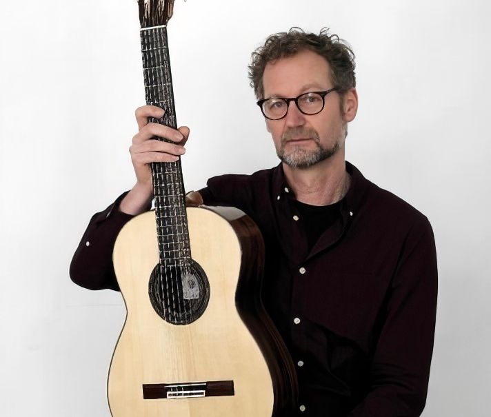 Hans van Velzen sitting down while holding one of his guitars