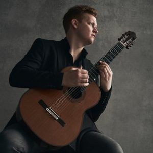 Campbell playing the guitar while looking to the right