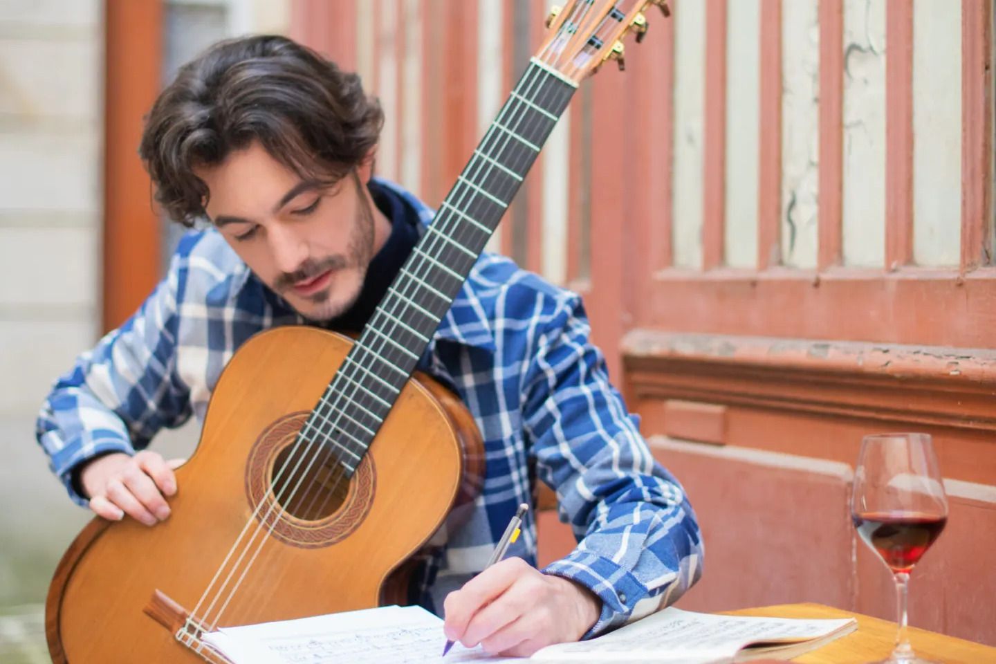 Gabriel Bianco writing sheet music while enjoying a glass of wine.