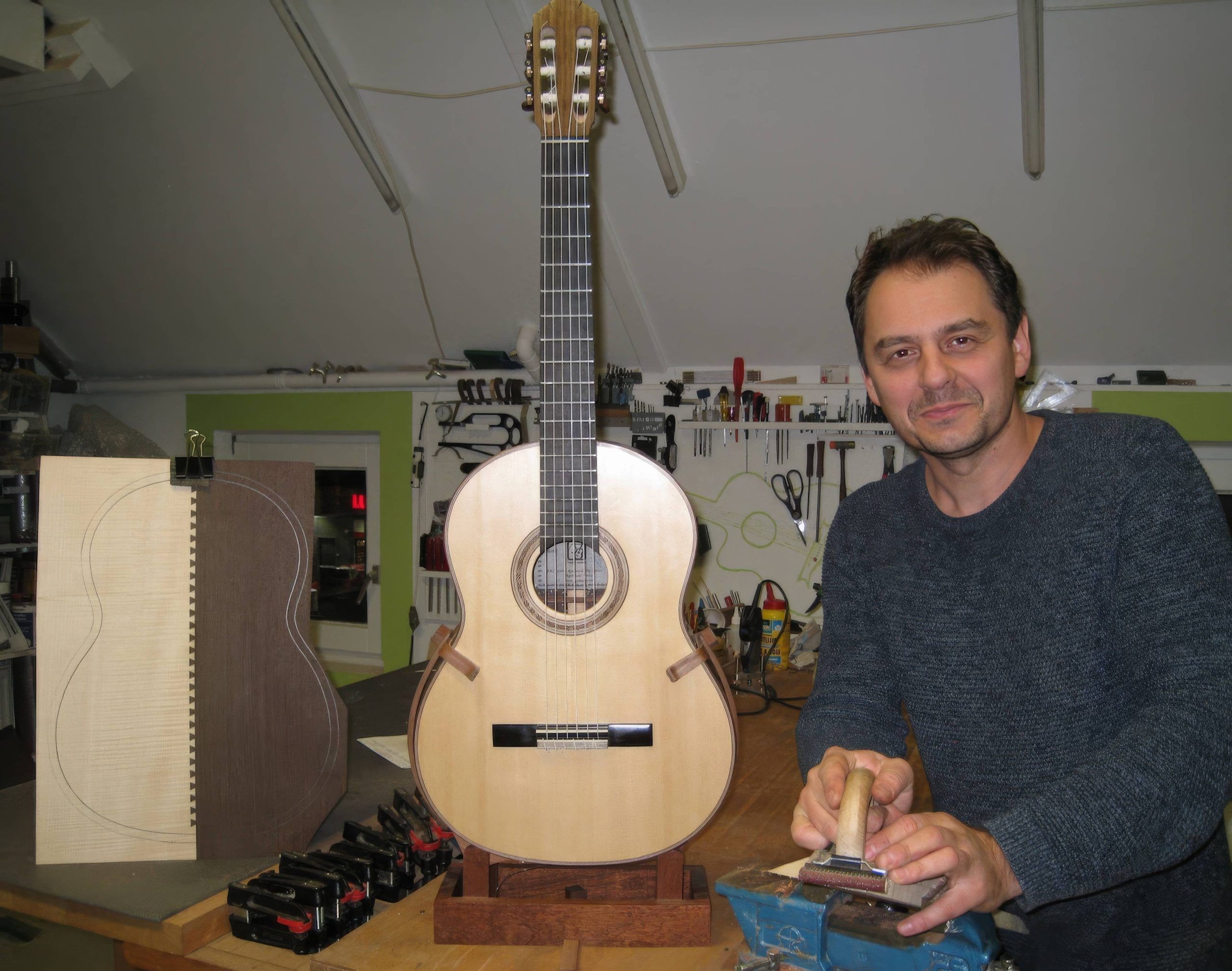 Tarik Saric in his workshop posing with his guitar.