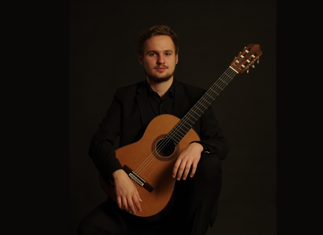 Luka Lovreković sitting in a chair with his guitar