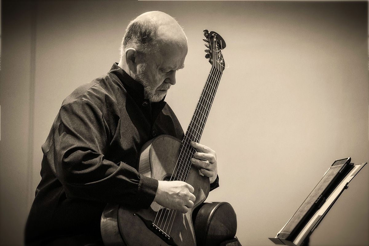 A monochrome image of Pavel Steidl playing on a romantic guitar.