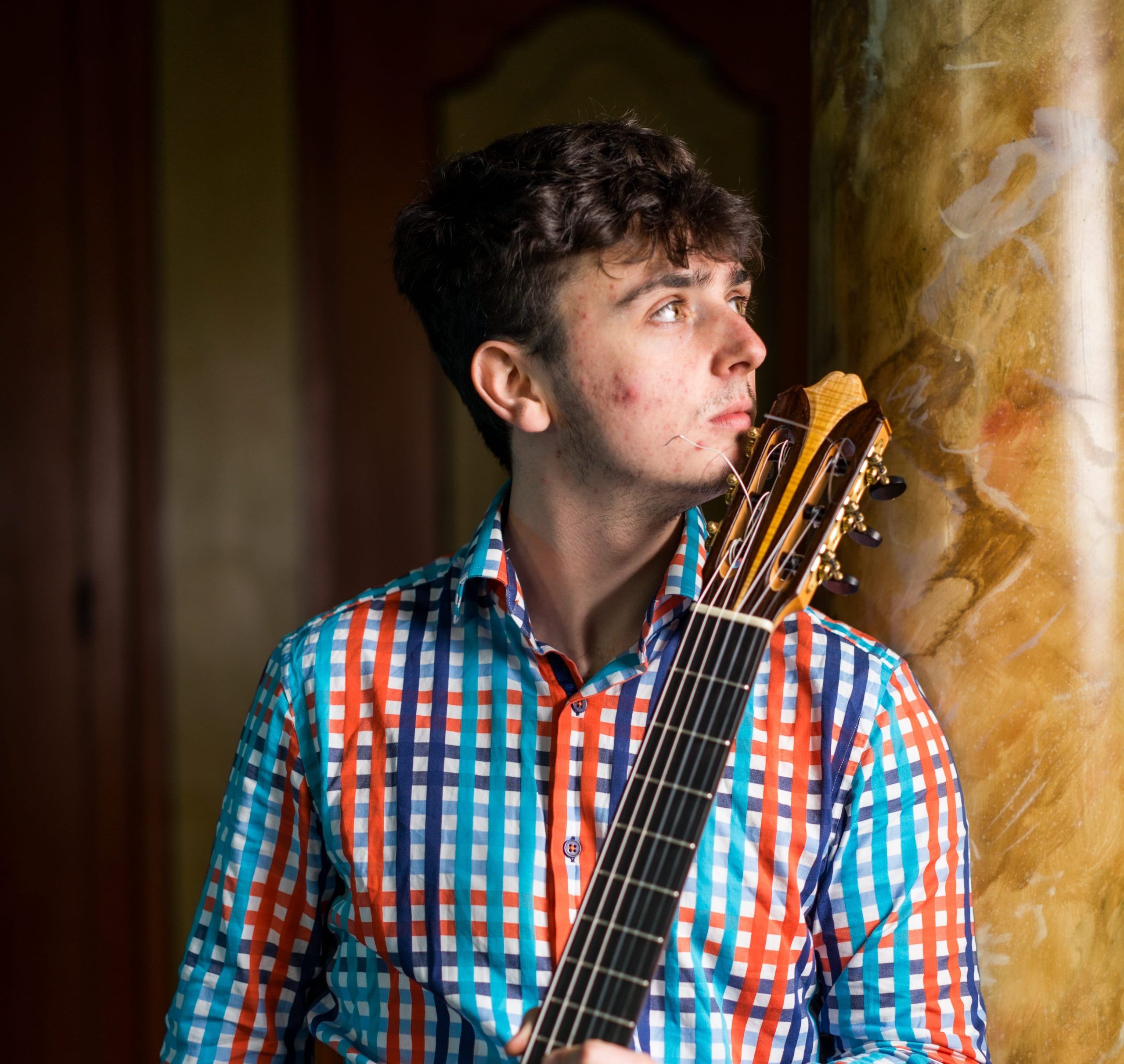 Mark Leighton in a colourful shirt holding his guitar.