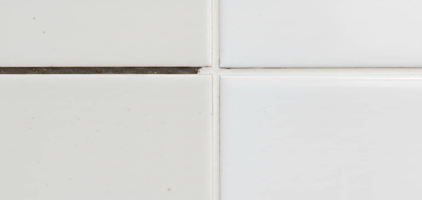 Confronto macro tra fuga porosa che assorbe macchie e fuga trattata con nanotecnologia che respinge i liquidi.