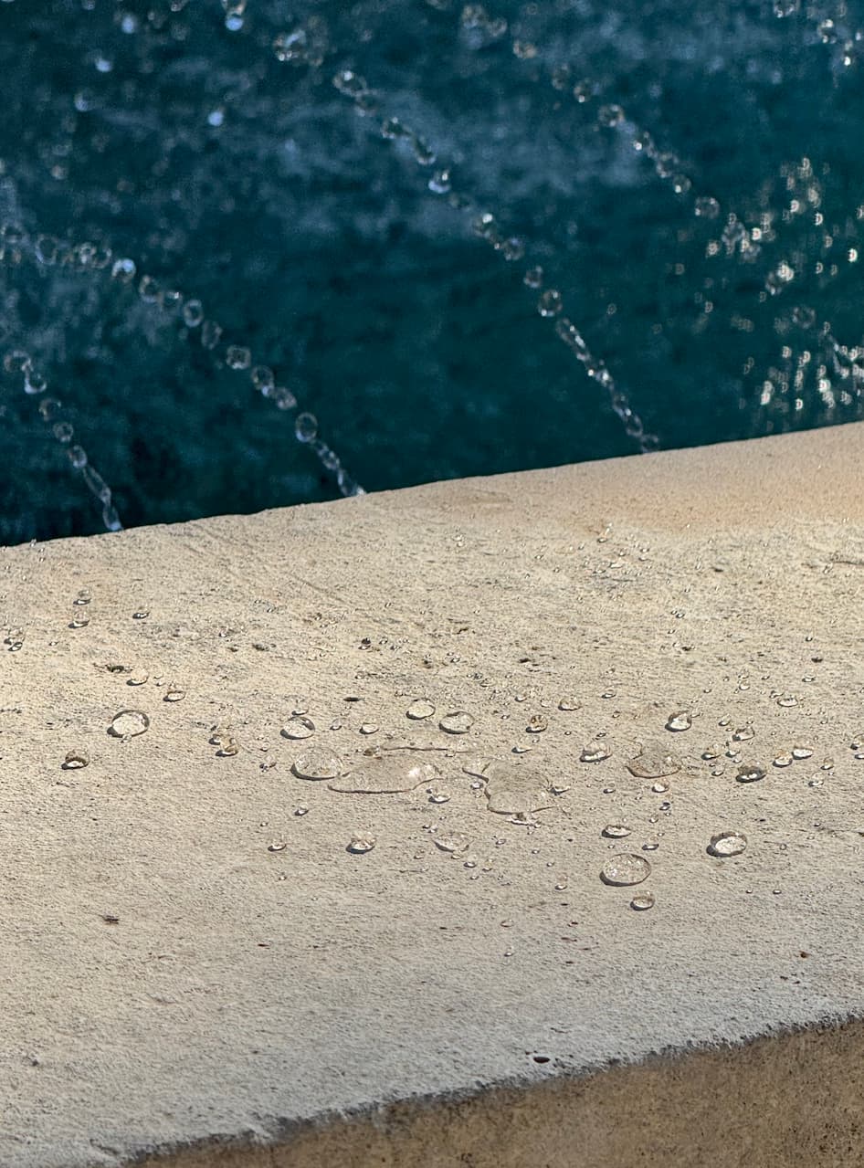 dettaglio di acqua sparsa sul bordo esterno della vasca in cui possono apprezzarsi chiaramente le gocce che formano l'effetto loto