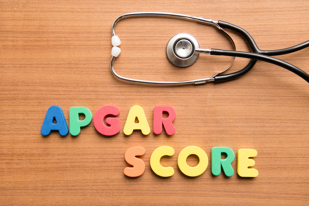 Image A medical stethoscope next to letters spelling out "APGAR SCORE," representing the evaluation of a baby before a potential NICU transfer.