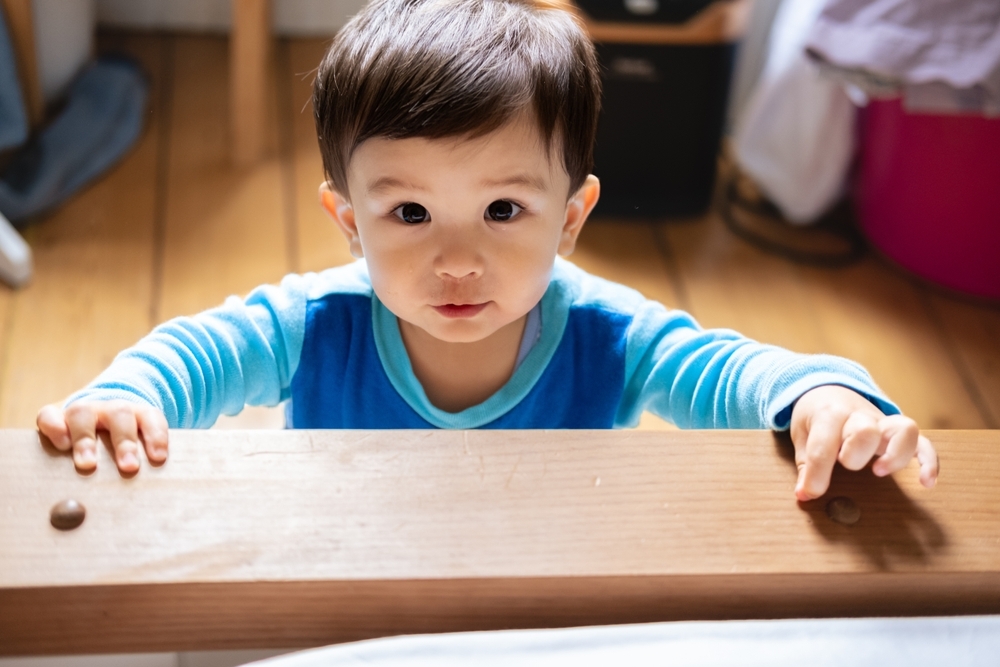 Image Baby standing and holding onto a wooden surface, symbolizing early developmental milestones and potential signs of birth injury.