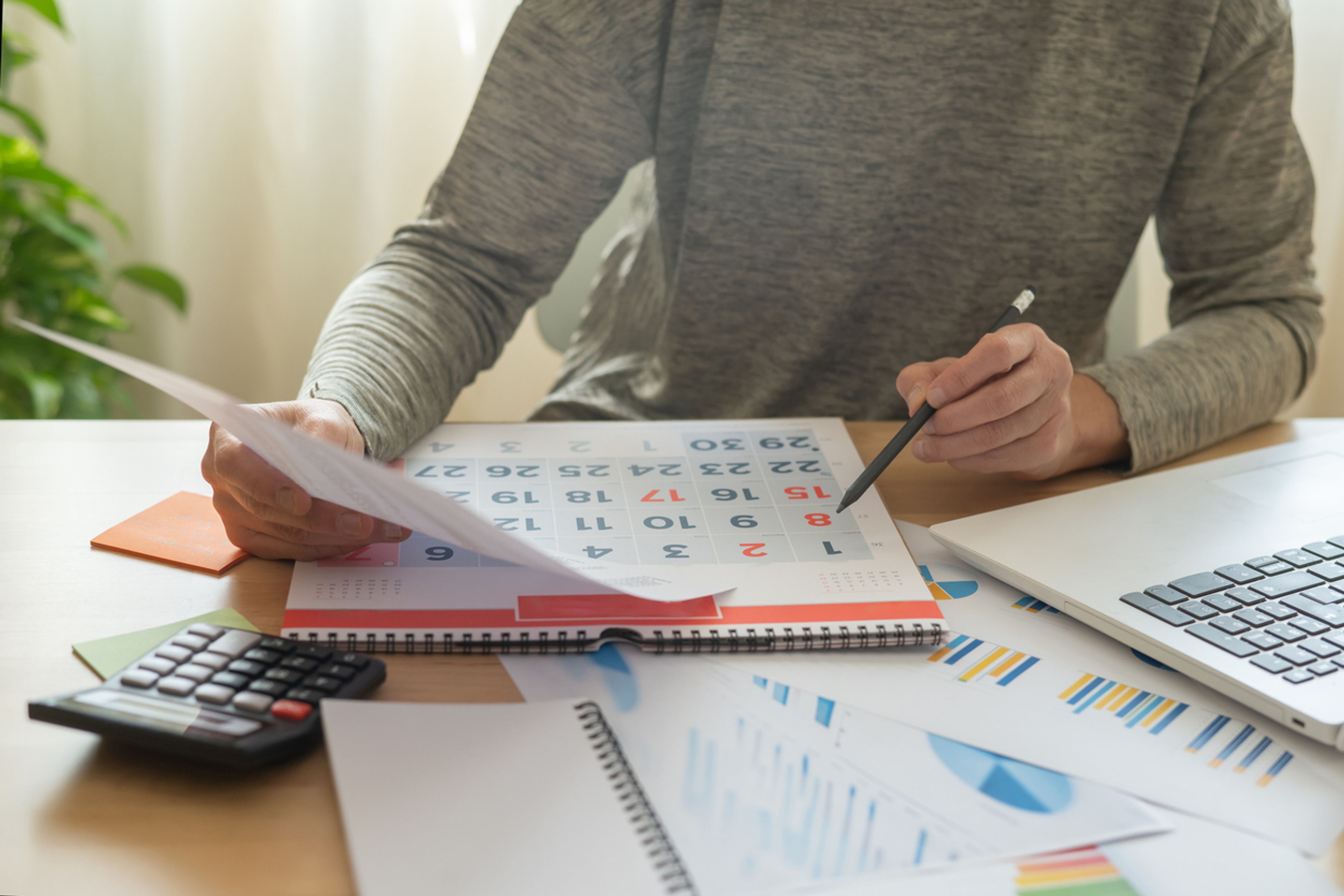 A person looks at a visa application and at a calendar to deciding if they want premium processing.