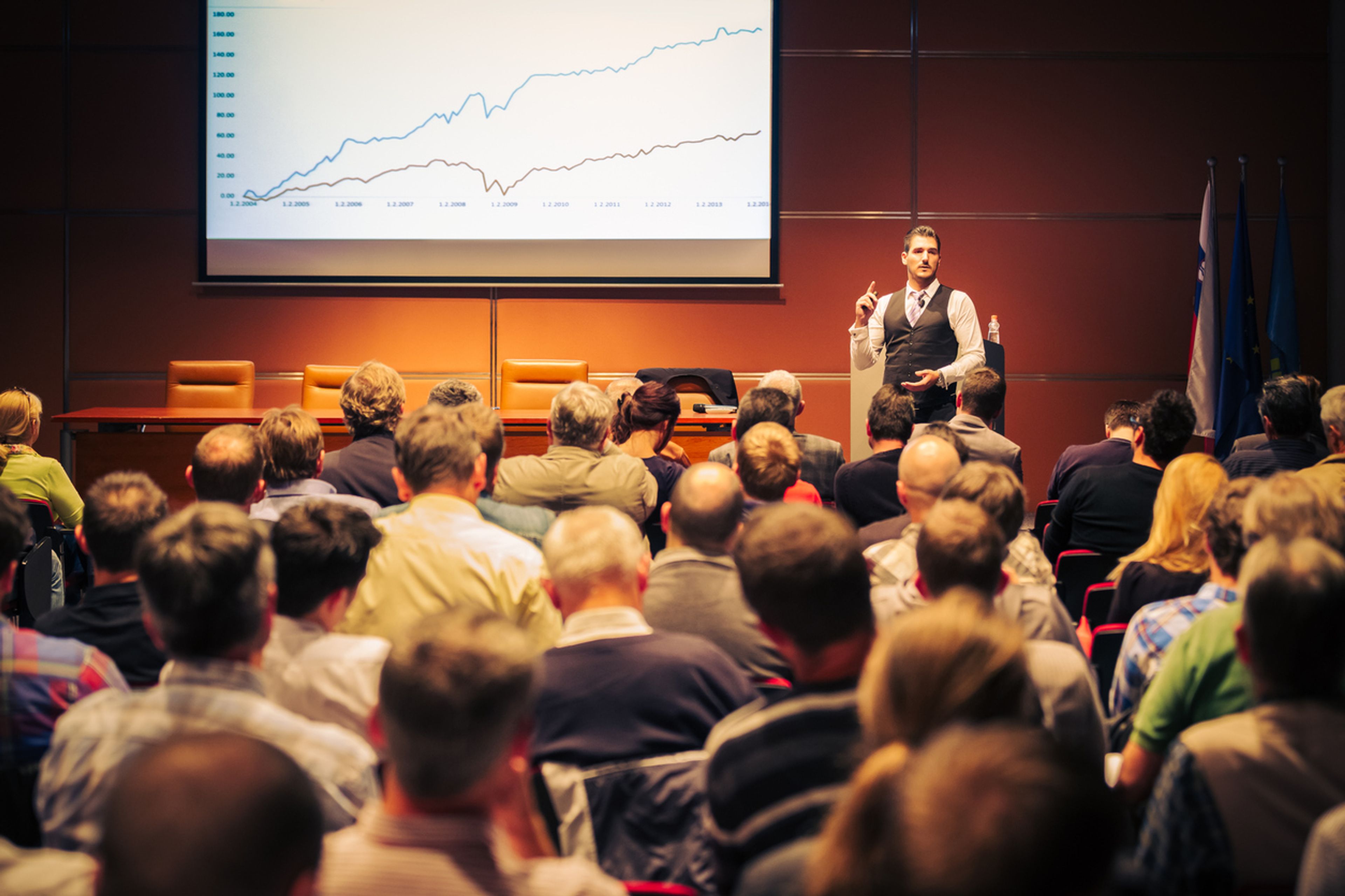 Executive presenting in front of a large audience at a conference.
