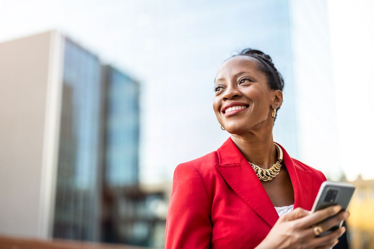 Confident businesswoman looking up from her phone after receiving good news.