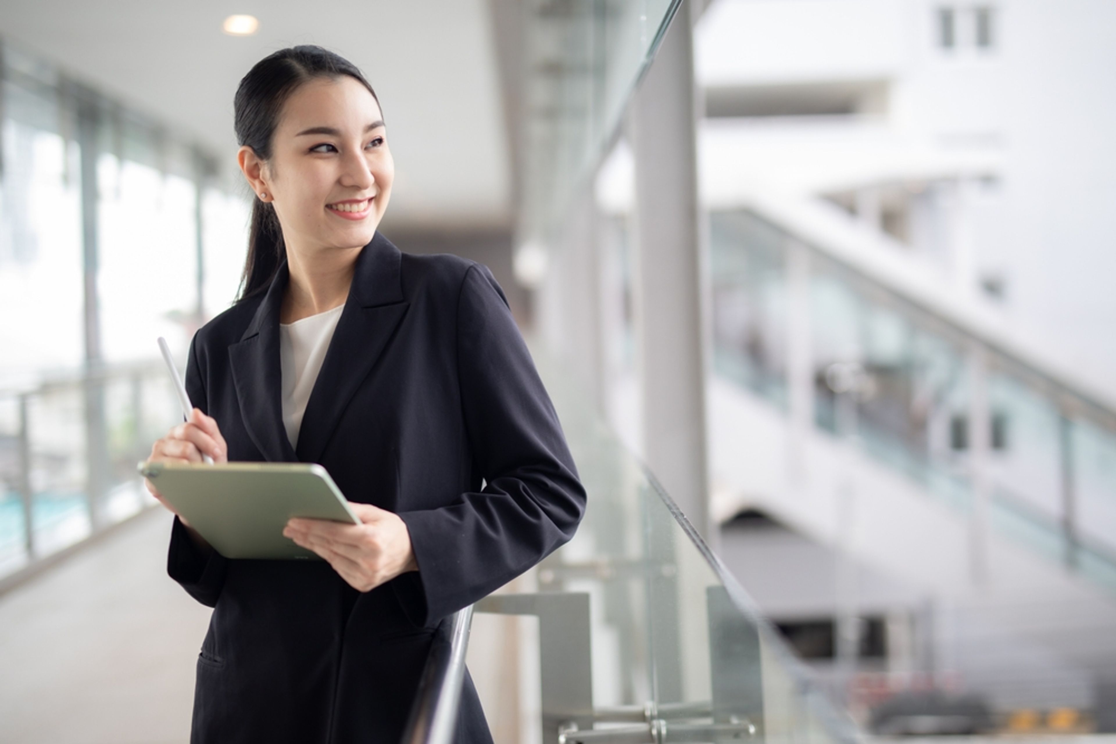 Excited office worker looking up from her tablet device.