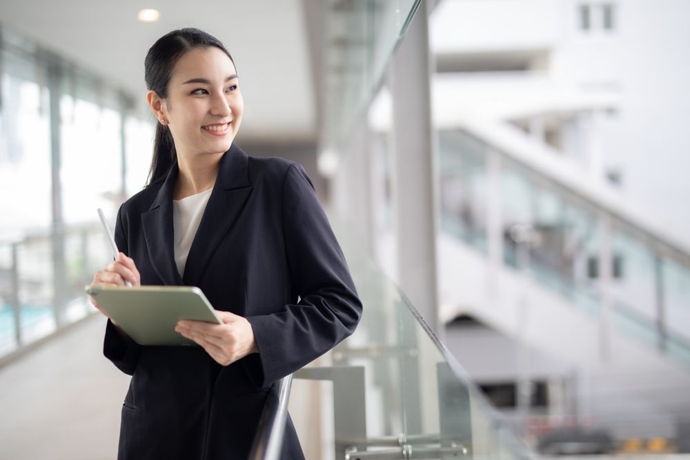 Excited office worker looking up from her tablet device.