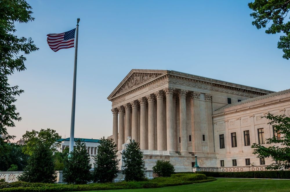 Side view of the United States Supreme Court building with an American flag flying in front.