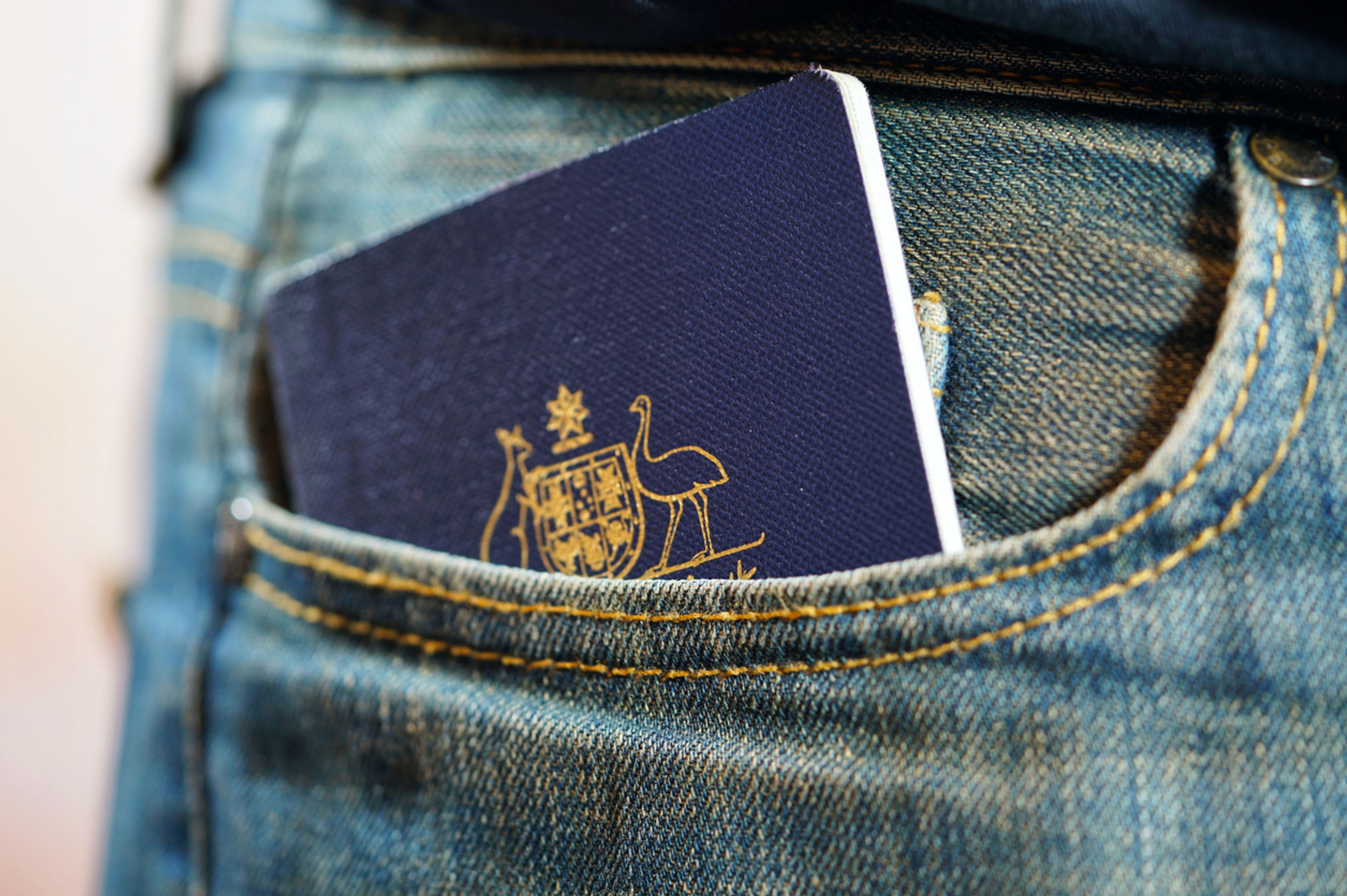 Closeup of an Australian passport hidden in the pocket of a jeans worn by a person.
