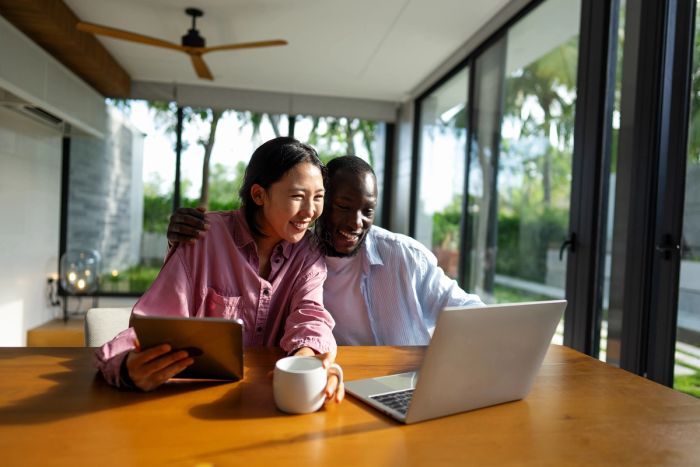 A couple looking at a laptop together and smiling excitedly.