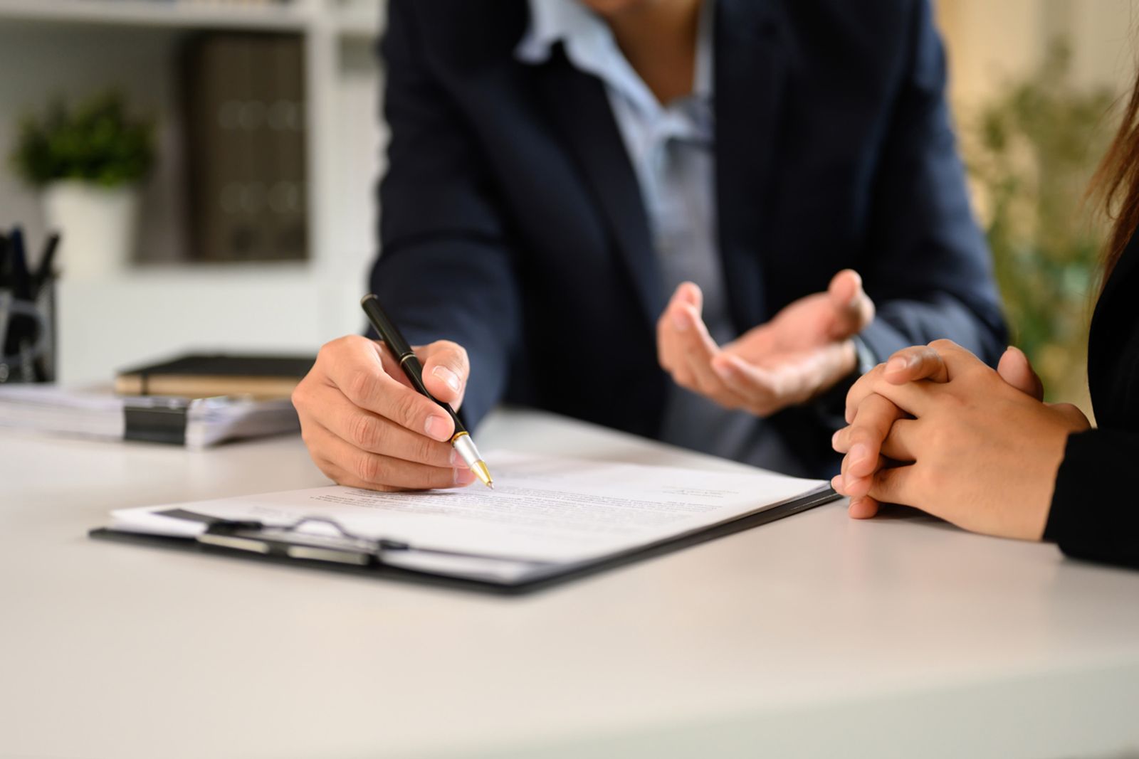 Attorney drafting a petition while advising a client across the table