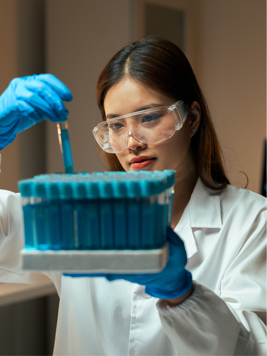 A researcher in a lab coat handling blue test tubes